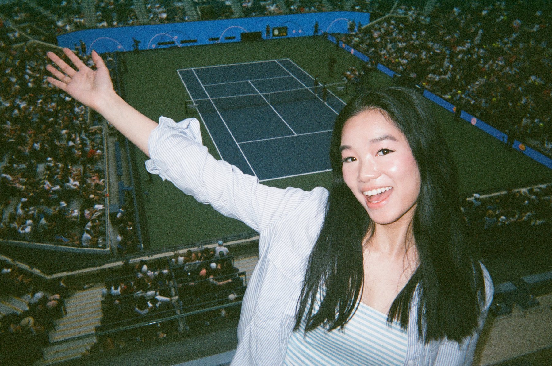 At a tennis match, waving to the camera