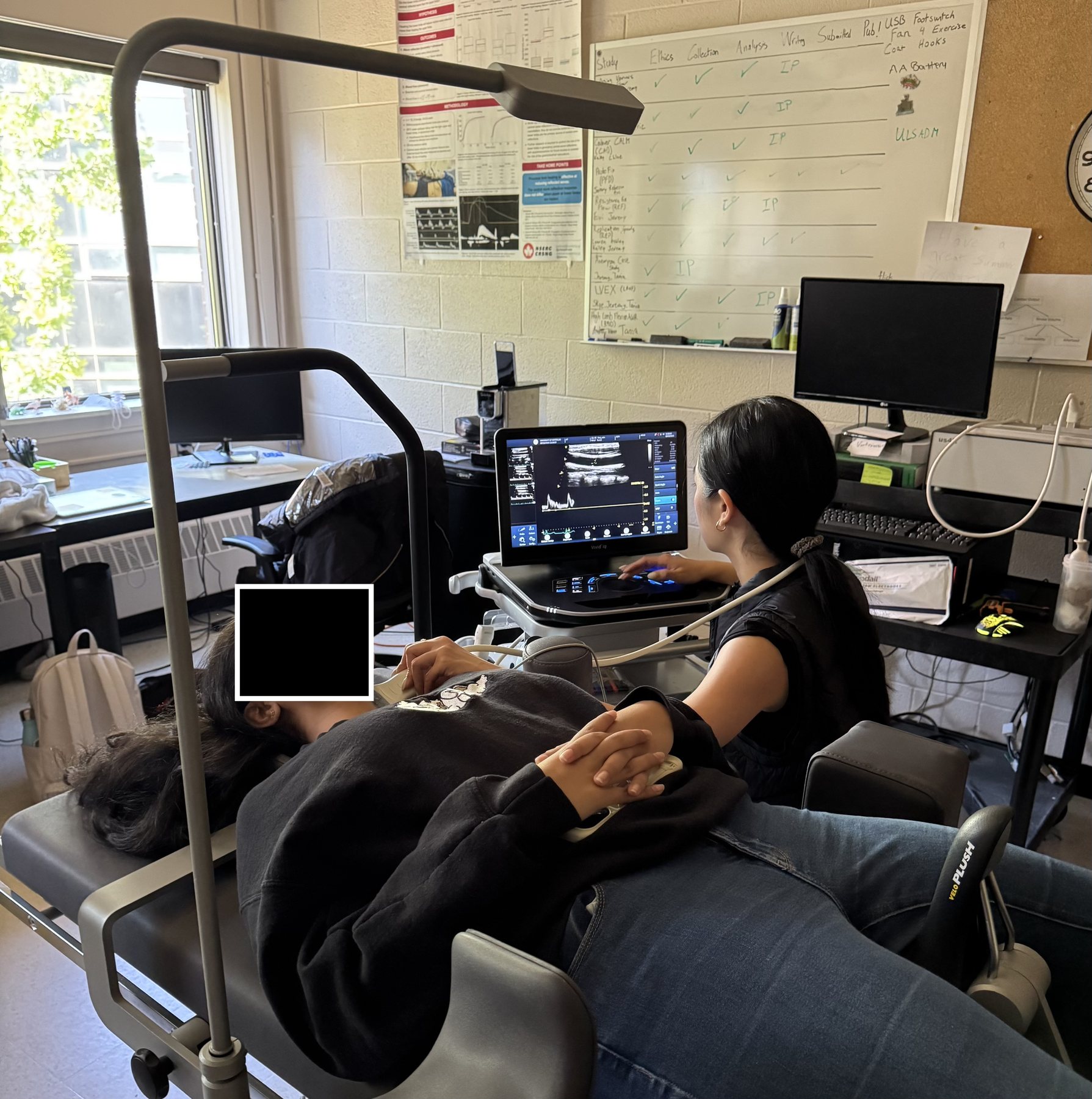 Performing a vascular ultrasound assessment on a study participant (participant's face blocked for privacy)